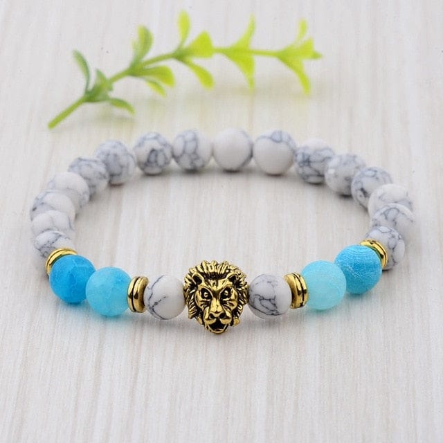 A gold lion crown head with blue and white marble color beads placed on a table. 